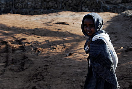 Smiling Child in Black Dress Shirt Walking on Brown Sand during Daytime thumbnail