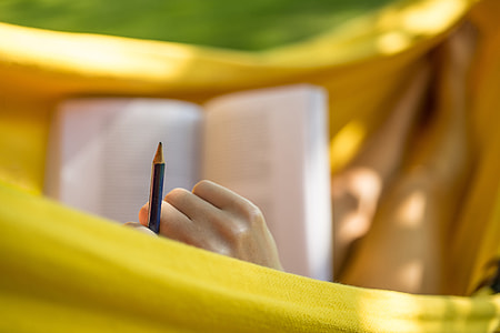 Woman studying and reading with pencil in garden thumbnail