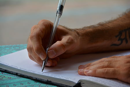 person holding pen on white book page thumbnail