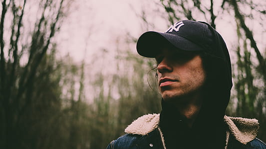 man wearing black cap and hoodie near grasses thumbnail
