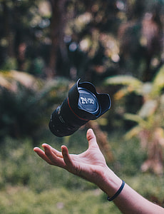 person catching black DSLR camera lens during daytime photography thumbnail