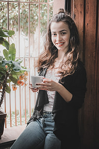 woman in black cardigan holding white ceramic mug near green leafed plant during daytime thumbnail