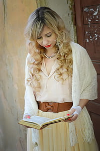 woman wearing white knitted headscarf and beige bow-accent dress holding book thumbnail