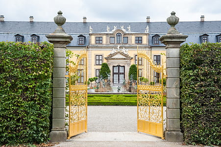 opened yellow metal gate in front of beige and gray concrete building during daytime thumbnail