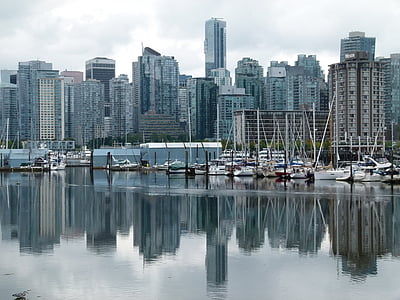 calm body of water near sailboats and high-rise building under cloudy sky at daytime thumbnail