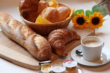 french bread, croissant, butter, and cup of coffee on brown wooden table thumbnail