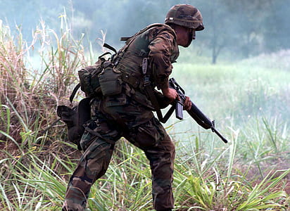 army walking along green grass thumbnail