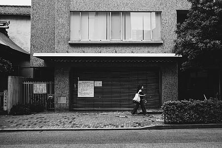 woman walking beside house during daytime thumbnail