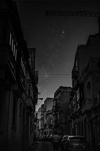 grayscale photography of vehicles parked in between buildings thumbnail