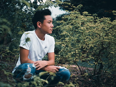 man squatting beside green leaf trees during daytime thumbnail