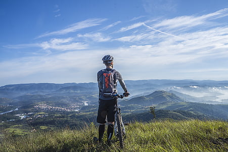 person with bicycle standing near mountain range thumbnail