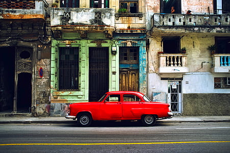classic red coupe beside gray concrete building during daytime thumbnail