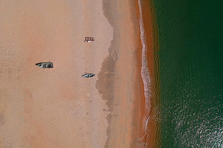 Aerial Photography of Two Gray Wooden Boats on Sand Front of Sea thumbnail