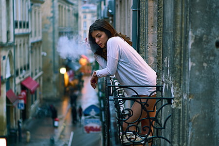 woman smoking cigar while standing on veranda thumbnail