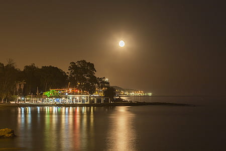 white concrete building beside calm body of water at nightime thumbnail