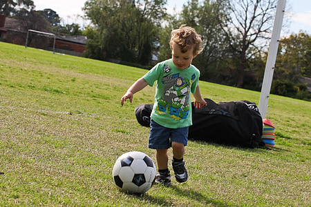 boy kicking soccer ball on grass field thumbnail