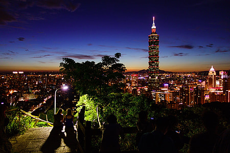 two girls sitting on stairs near tower buildings with lights at night thumbnail