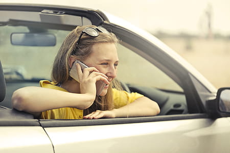 Blonde-haired Woman in Yellow T-shirt Wearing Black Sunglasses Holding Silver Smartphone thumbnail