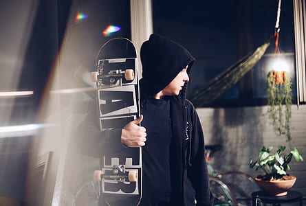man holding black wooden skateboard thumbnail