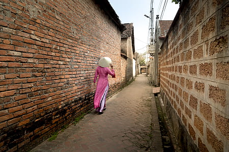 women's pink long-sleeved top walking near brick wall thumbnail