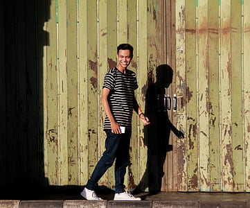 man standing behind yellow wall while smiling thumbnail