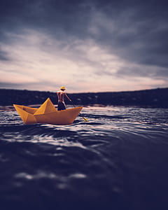 forced photography of yellow paper boat on body of water thumbnail