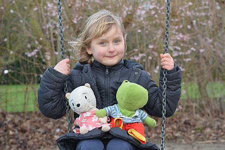 smiling girl wearing black bubble jacket on swing during day thumbnail