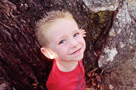 smiling boy leaning on tree trunk thumbnail