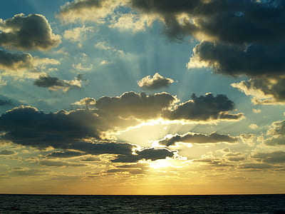 silhouette of beach under white clouds blue skies thumbnail