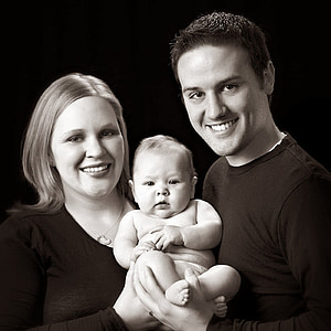 gray scale photo of man and woman carrying baby thumbnail