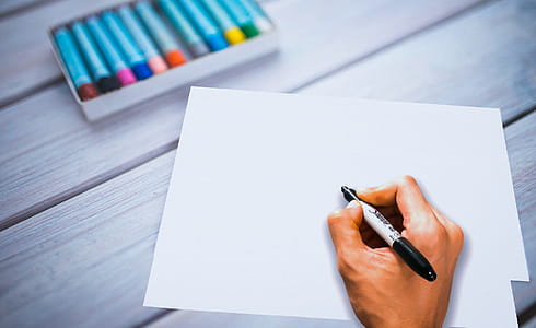 Photo of a blank piece of paper with a hand holding a marker, ready to write. thumbnail