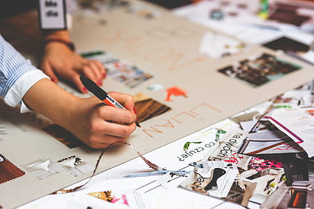 person writing on white printed paper using black and orange ballpoint pen thumbnail