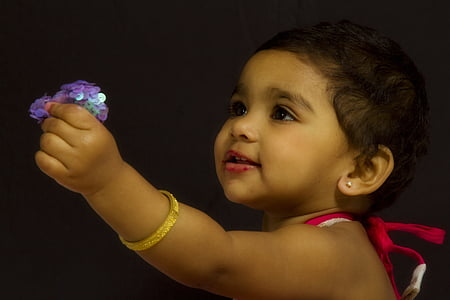 baby holding purple sequined flower thumbnail