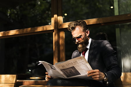 man wearing black and white tuxedo suit reading newspaper during daytime thumbnail