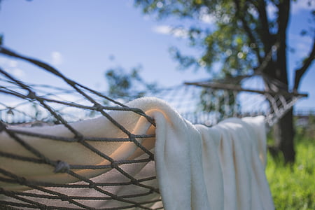 white blanket on gray rope hammock outdoor during daytime thumbnail