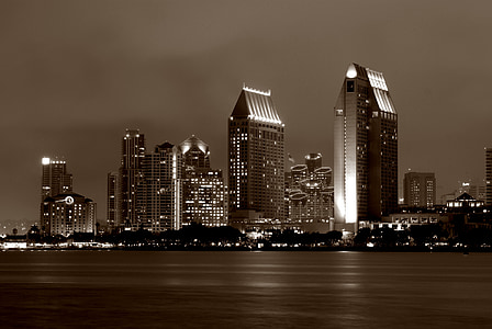 grayscale photography of cityscape by water thumbnail