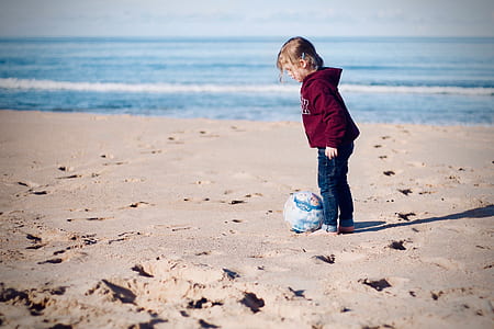 child standing on beige sand near teal ball thumbnail
