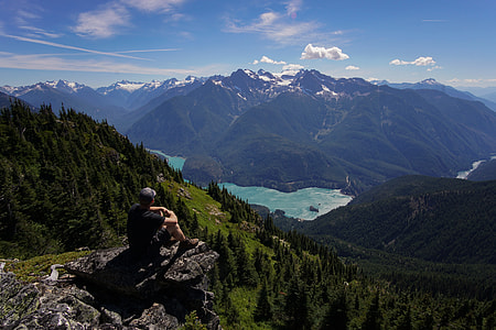 man sitting on the cliff in front of hills thumbnail