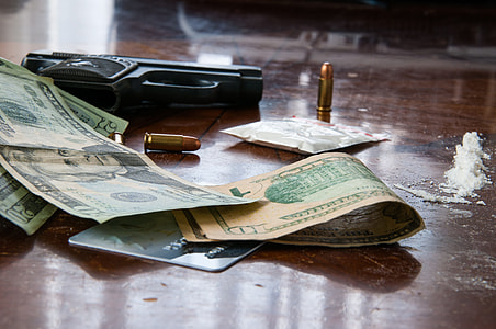 U.S. Dollar bills near black semi-automatic pistol on wooden surface thumbnail