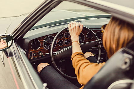 brown haired woman sitting inside car while holding steering wheel thumbnail
