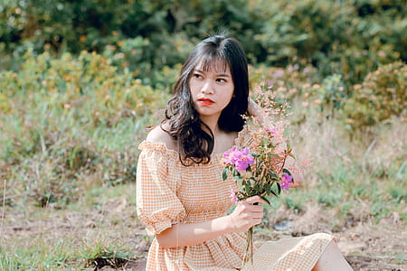 Woman in Orange and White Tattersaal Off-shoulder Dress Holding a Pink Flowers thumbnail