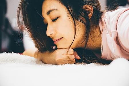 woman in pink shirt laying on white textile thumbnail