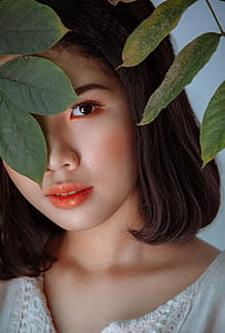 Photography Of Woman Hiding Behind Leaves thumbnail
