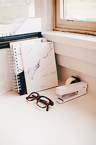 white stapler; notebook; and sunglasses with black and brown frames thumbnail