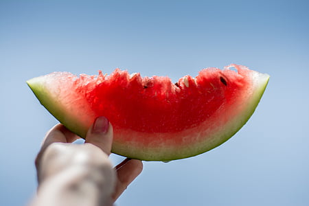 person holding sliced red watermelon thumbnail