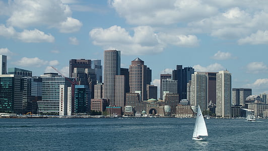 sail boat on body of water in distant of skyscrapers thumbnail