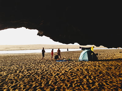 people standing near blue tent under cave thumbnail