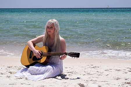 Blond Woman Playing Spruce Top Dreadnought Acoustic Guitar by the Seashore thumbnail