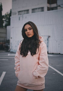 woman wearing pullover hoodie standing against white wall thumbnail