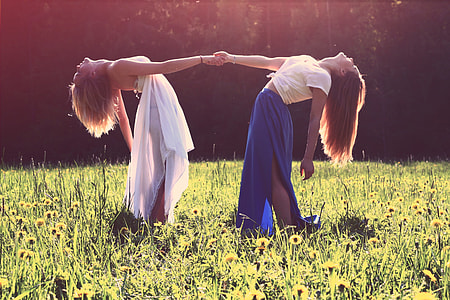 two women standing on green grass field while holding hands during daytime thumbnail